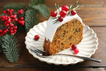 Slice of tasty Christmas cake with cranberries served on wooden table, closeup