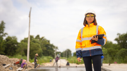 A construction worker monitors road work in an urban setting, wearing safety gear and holding a...