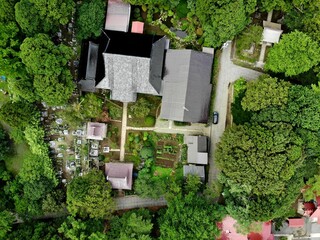 Top down drone view of Buddhist temple, cemetery and gardens in lush forest at Matsumae, Hokkaido, Japan