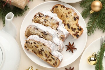 Slices of traditional Stollen, teapot and Christmas decor on white table, flat lay