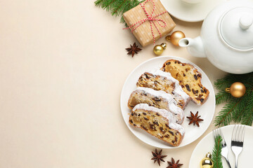 Slices of traditional Stollen, teapot and Christmas decor on white table, flat lay. Space for text