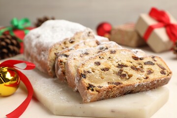 Cut traditional Stollen cake and Christmas decor on white table, closeup