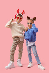 Happy little children in Christmas reindeer horns on pink background