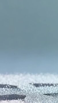 Vertical video: Swirling snow around silver clock in gray haze, veiling face and settling on ground
