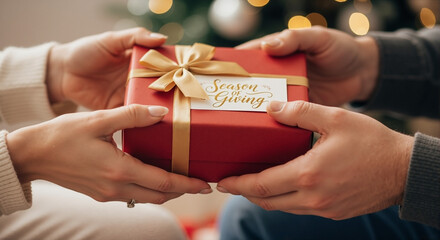 Exchanging gift box with card wishing season of giving, hands pass festive present tied with golden ribbon. Season of giving shared between people and represents holiday cheer.