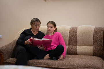 A grandmother and granddaughter share a heartwarming moment as they sit together, engrossed in a photo album, creating lasting memories.