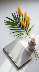Photo of still life of a closed notebook, a vase with yellow flowers