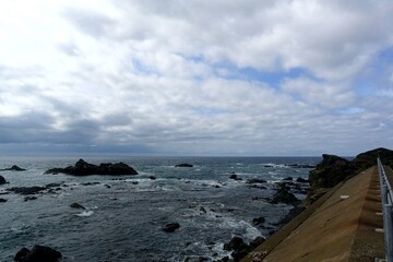 Rocky Tsugaru Strait shoreline and seawall under dramatic clouds at Matsumae, Hokkaido, Japan