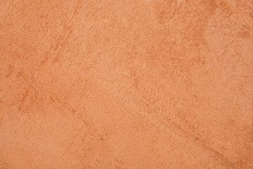 A full frame, close-up view of a soft orange-brown suede or microfiber textile with an uneven, slightly brushed texture