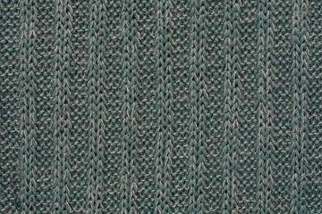 A detailed, full-frame close-up of a tightly woven, geometric rib knit fabric in a muted blue-gray color, creating a repetitive diamond-like texture