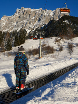 Small child learning to ski using magic carpet on sunny day, Ehrwald, Zugspitze, Austria