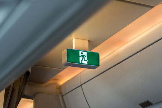 Airplane green emergency exit sign illuminated inside the cabin of passenger jet.
