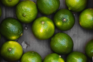 Fresh green limes arranged on a dark surface in a vibrant display at a market or grocery store