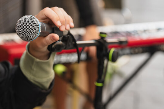 Performing musician prepares to sing into microphone at a live music event outdoors in the afternoon