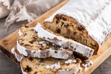 Traditional Christmas Stollen with Raisins and Powdered Sugar on wooden table
