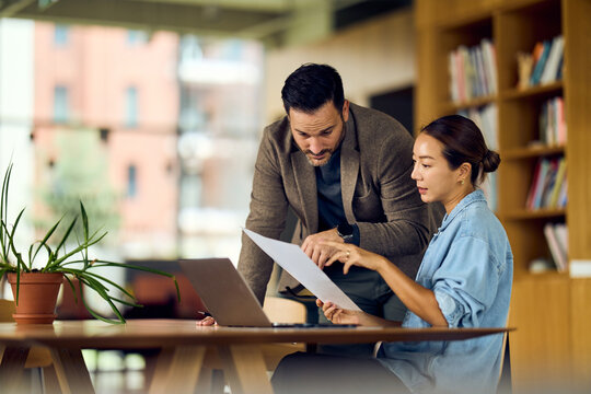Professional Meeting Between Man And Woman Discussing Documents In Modern Office Library