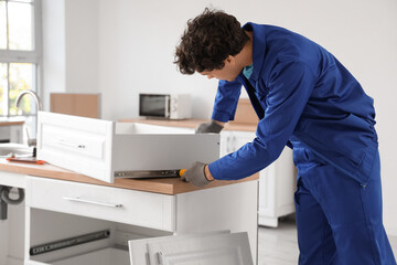 Male worker assembling drawer in kitchen