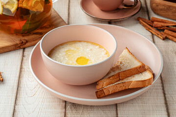 Warm creamy rice porridge with melted butter served with toasted bread on a pink plate