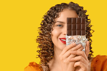 Beautiful young woman with chocolate bar on red background