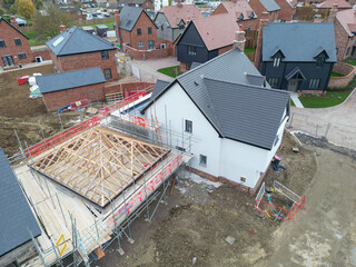 Near completed large, detached family home seen with its partially completed detached garage located on a new housing development in rural Britain.