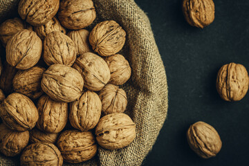 A lot of walnuts in shells in burlap on a dark background. The best source of strength, energy and vitamins for a healthy diet