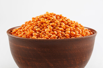 Clay cup with red lentils on white background.