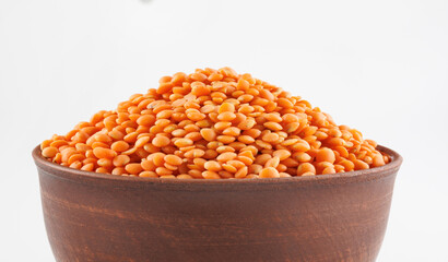 Clay cup with red lentils on white background.