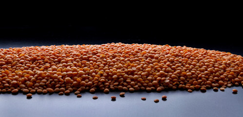 A large pile of red lentils on a black background.