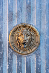 Decorative golden lion head fountain ornament on textured blue wall in Senj, Croatia