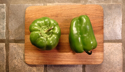 two green bell peppers on a wooden table