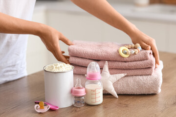 Woman with baby milk formula and accessories on table in kitchen, closeup