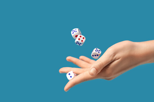 Female hand throwing game dices on blue background