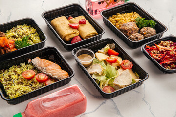 Balanced healthy meals in black containers with fish, meat, vegetables, and salad for food delivery service