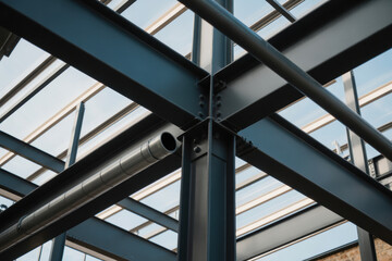 Obraz premium Modern steel framework with metal beams and pipe installation at a construction site during structural building phase outdoors