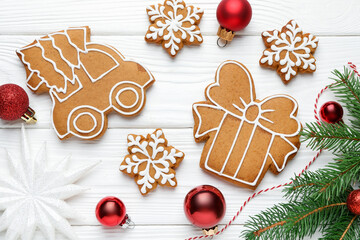 Tasty gingerbread cookies and festive decor on white wooden table, flat lay