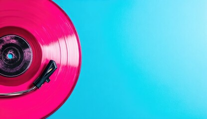 Pink vinyl record on a blue surface with a stylus.