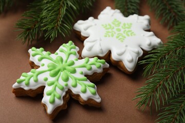 Tasty gingerbread cookies and fir tree branches on brown background, closeup. Christmas treat