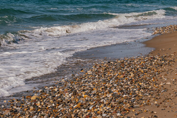 Beach texture: a mix of round pebble, frothy sea foam, and clear water at the shoreline