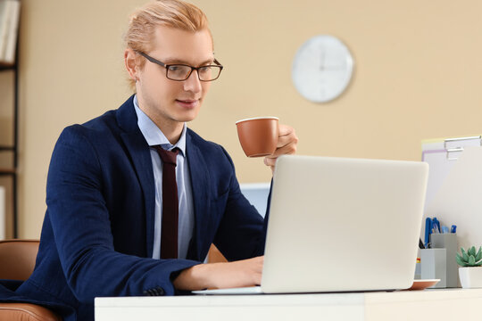 Young businessman working with laptop and coffee at desk in office