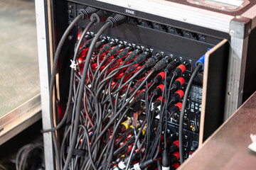Many electrical wires connected to professional stage equipment, forming part of the concert’s sound and lighting system setup backstage
