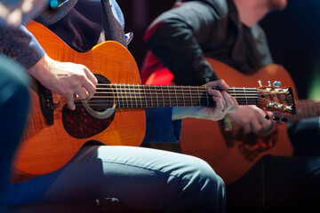 Male musician performing on stage and playing electric guitar during a live concert show with stage lights and sound equipment