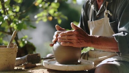 A skilled artisan shaping a clay pot on a pottery wheel, surrounded by lush greenery and natural light