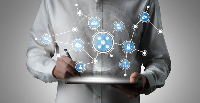 A businessman interacts with a digital tablet while engaging with connected data icons representing cloud technology and business analytics in a modern workspace. Tessel
