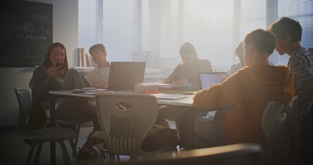 Diverse Group of Students Gathers Around Central Table, Working Together Intensely on Laptops. Collaboration, Group Project Work, and Essential Role of Digital Learning in Modern Educational Setting.