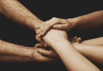 Fototapeta premium Young people putting their hands together on dark background, closeup
