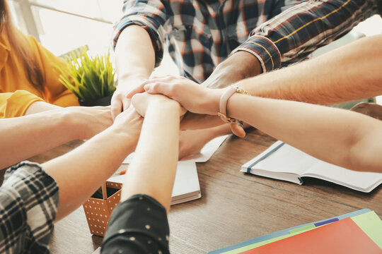 People putting hands together at table, closeup. Unity concept - Powered by Adobe