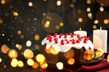 Tasty Christmas cake with red currants and candles on table. Bokeh lights