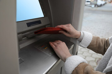Woman entering cash machine pin code and covering hand with wallet, closeup