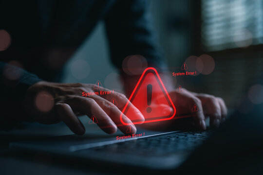 Hands typing on a keyboard with red system error warning icon. Concept for cybersecurity threats, system failure, hacking alert, IT issues, malware detection, and critical tech problems.