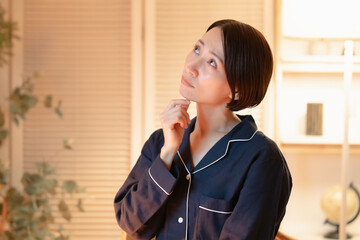 悩むパジャマ姿の女性